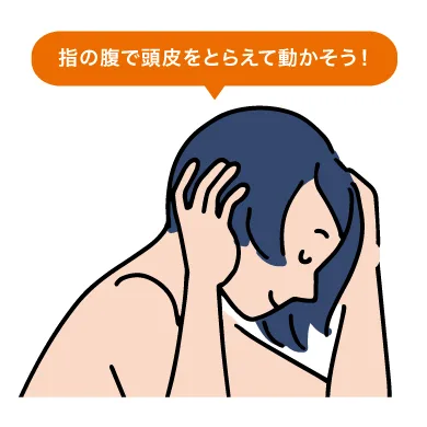 紺色の髪の女性が下を向き、両手の指の腹で頭皮をつかむようにしてマッサージしています。「指の腹で頭皮をとらえて動かそう！」と書かれた解説イラストです。