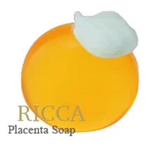 白い背景に泡をのせたオレンジ色の丸い石けんが2個並び、「RICCA Placenta Soap」と書かれています。